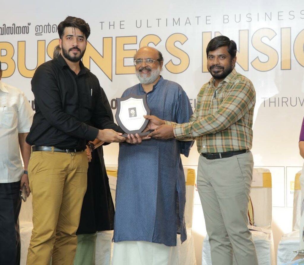 Three people on a stage holding a shield-shaped Emerging Brand award plaque.