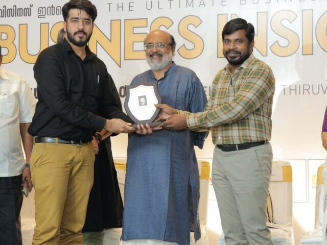 Three people on a stage holding a shield-shaped Emerging Brand award plaque.
