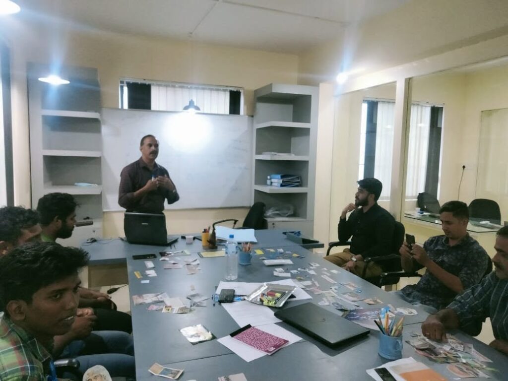 Vision Board training held in Palakkad in 2022 5 Team members seated around a meeting table while a trainer speaks beside a whiteboard.