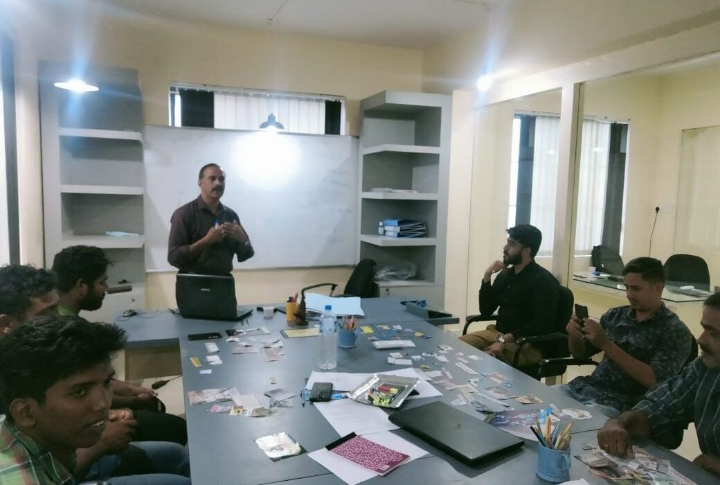 Vision Board training held in Palakkad in 2022 1 Team members seated around a meeting table while a trainer speaks beside a whiteboard.